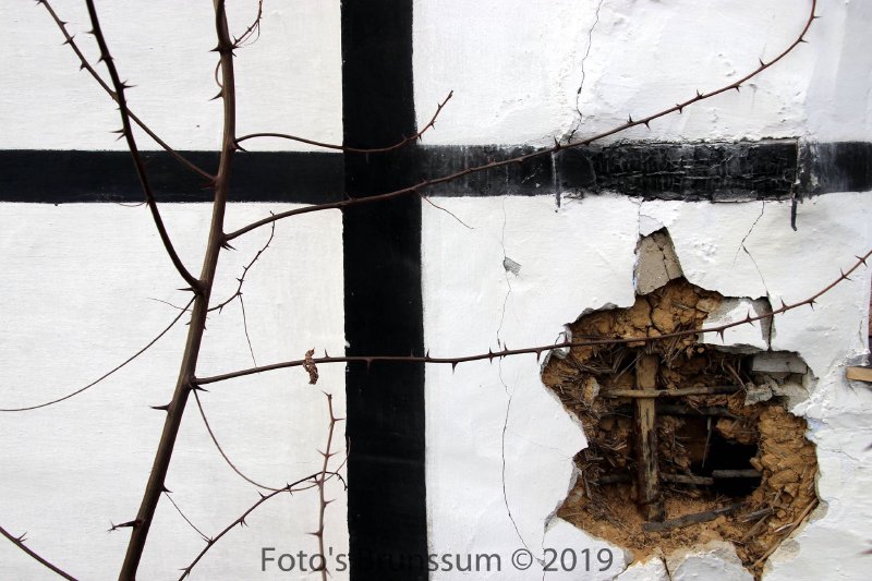 Close-up of cracked wall panel with exposed straw-and-clay infill